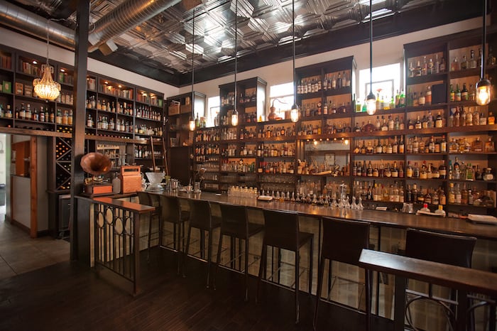 Seattle’s Canon bar with its floor-to-ceiling whiskey bottle display and dim speakeasy lighting Title: Canon – The Whiskey Library
